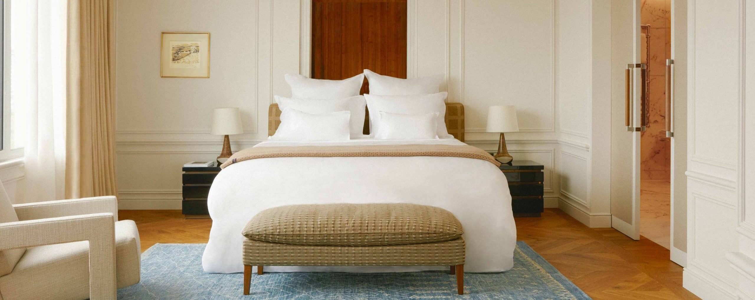 Neatly arranged bedroom with a bed, ottoman, and decor.