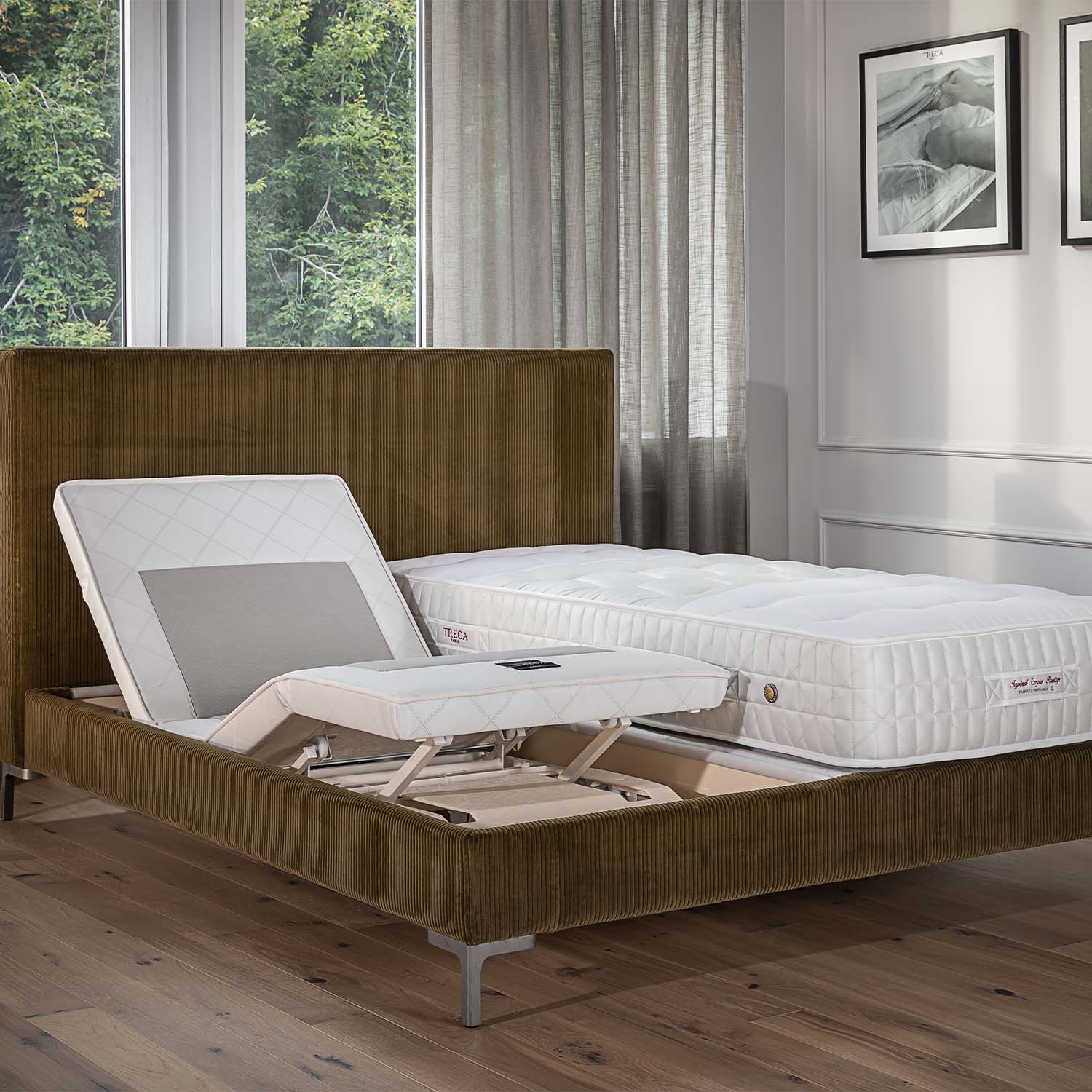 Brown bed with Treca supercad bed base and a mattress in a room with large windows and curtains.