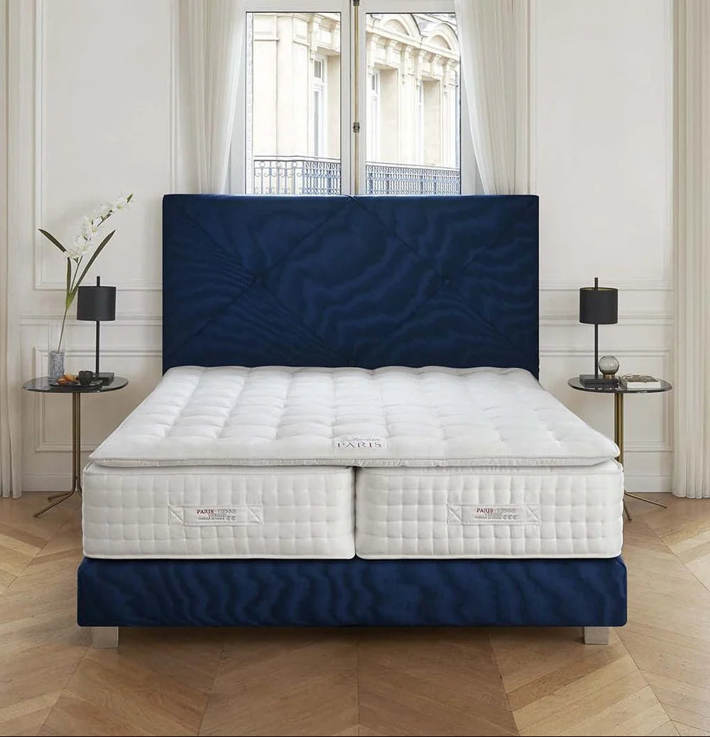 Treca Paris Vienne Venise mattress on a blue bed frame in a room with large windows and decorative elements.