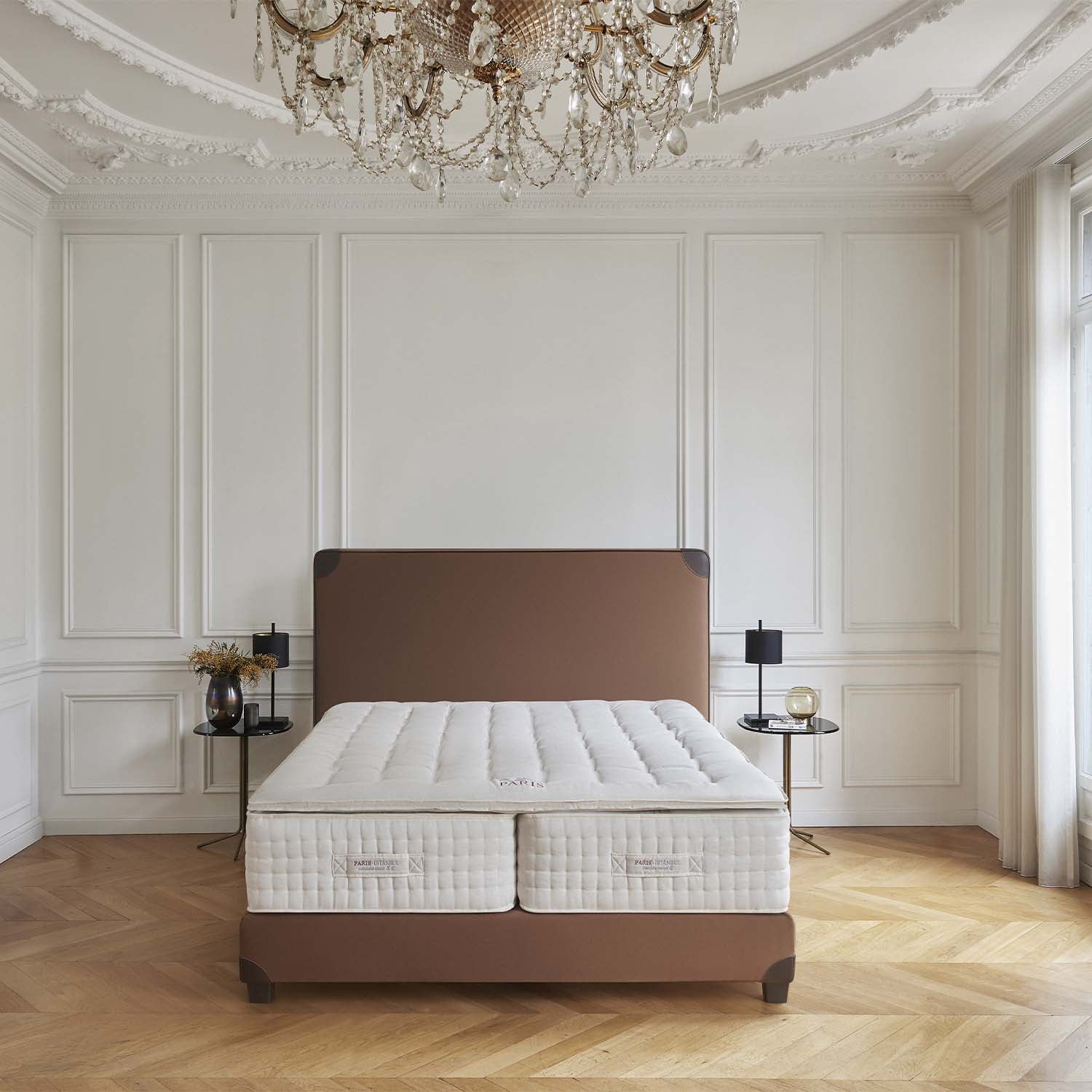 Bed with white mattress and Treca Paris topper in a luxurious bedroom with a chandelier.