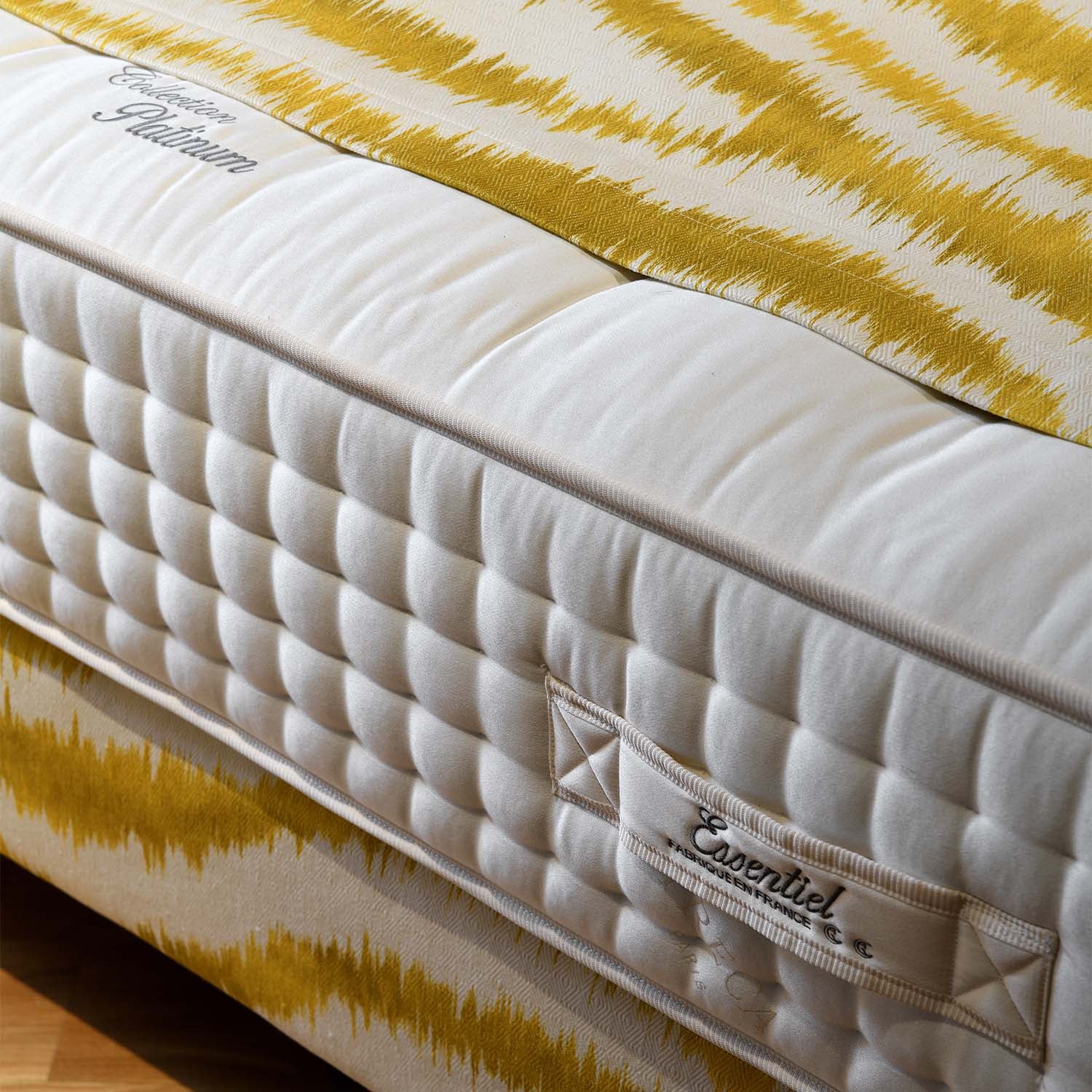Treca Platinum Essentiel mattress with yellow and white striped cover on a wooden floor