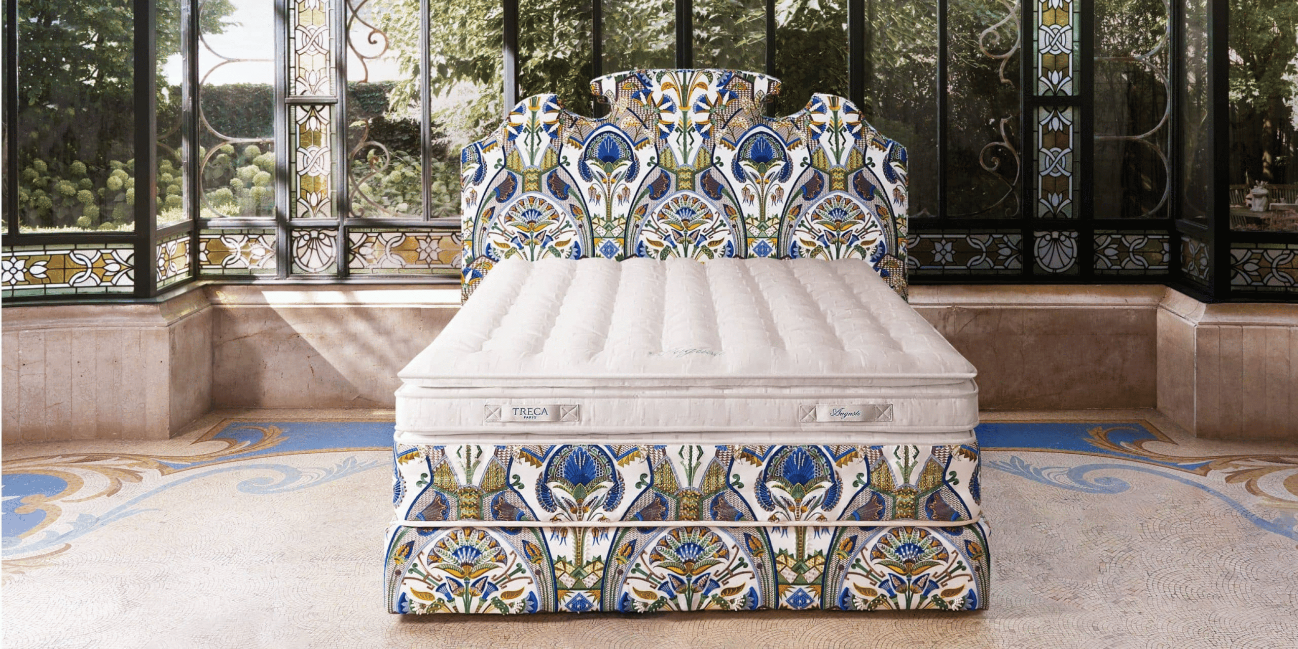 A Treca auguste bed in a stylish room withtainted windows 