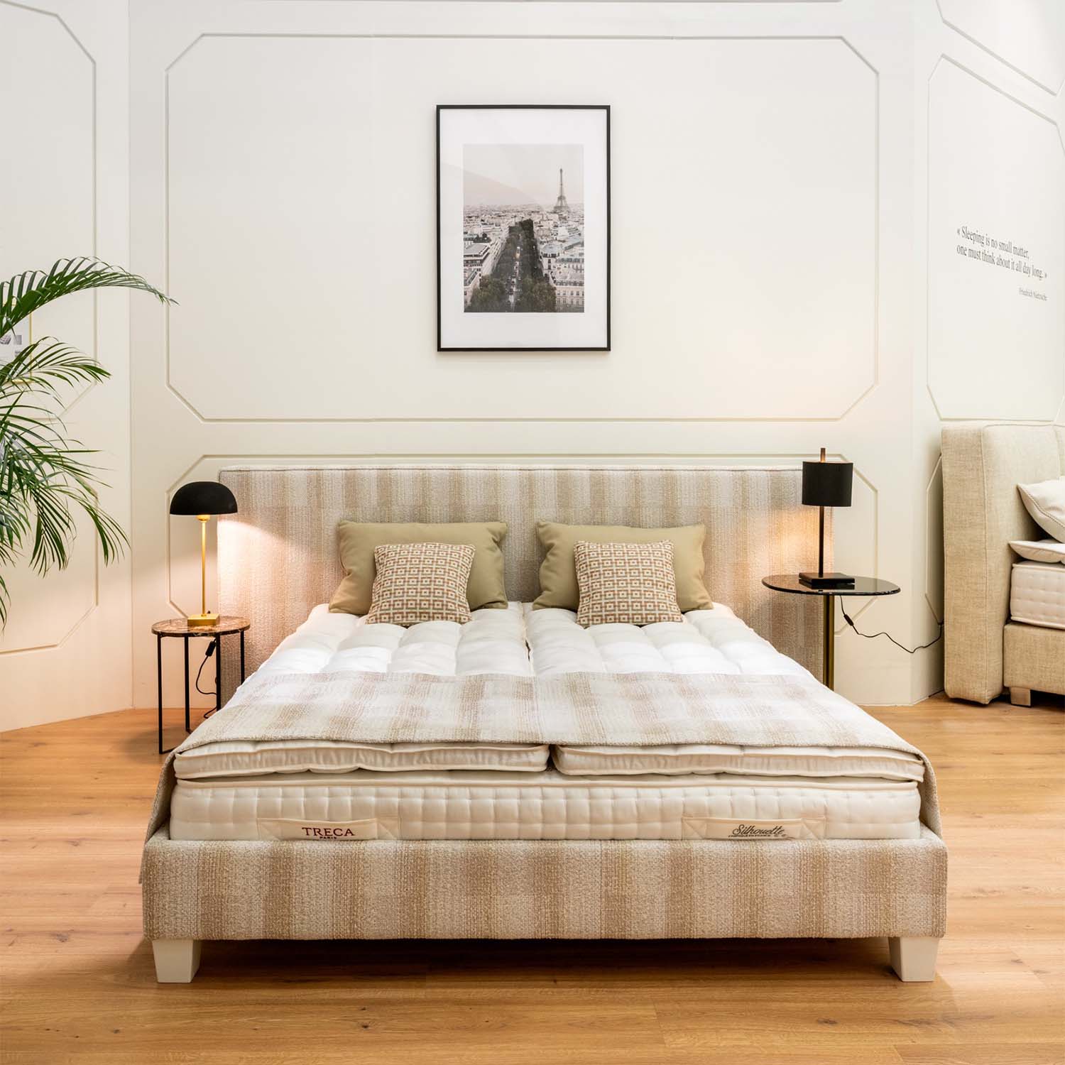 Bedroom with a bed featuring a Treca miniflex bed base, mattress, pillows, and a lamp on a nightstand.