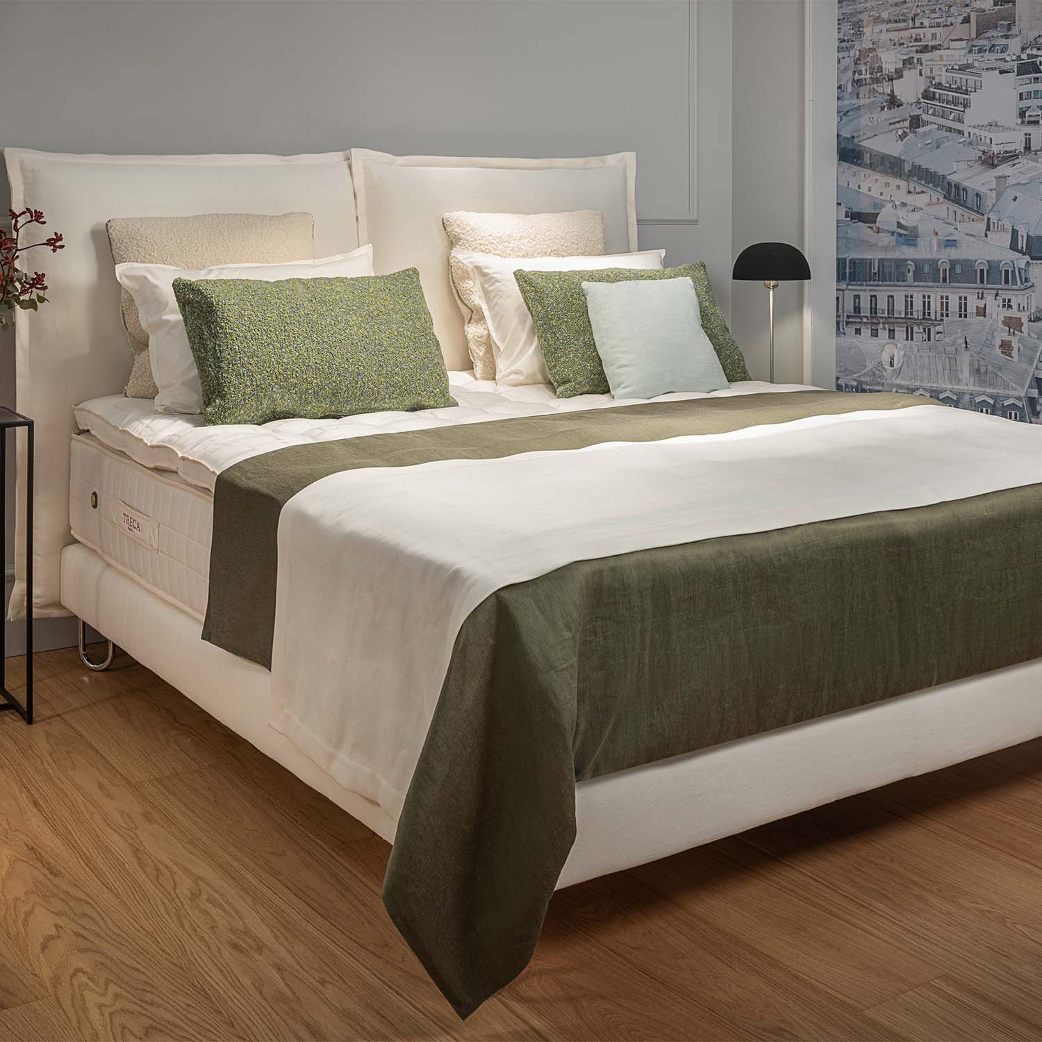 Bedroom with a neatly made bed featuring a Treca grand confort bed base with green and white bedding.
